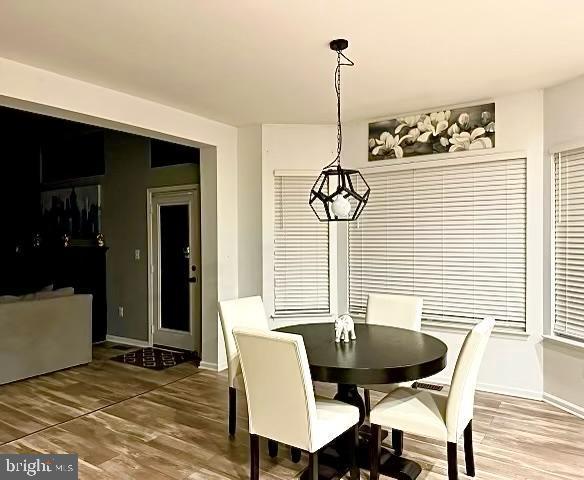 dining area with baseboards, an inviting chandelier, and wood finished floors