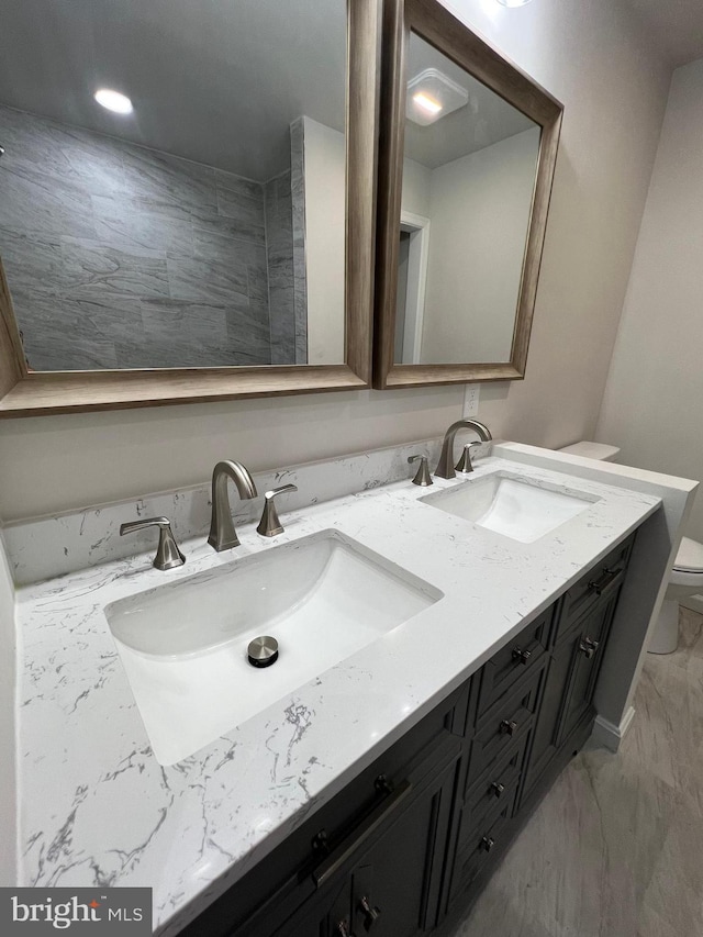 full bathroom featuring double vanity, marble finish floor, toilet, and a sink