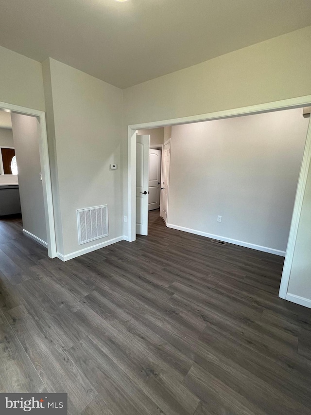 unfurnished bedroom featuring visible vents, baseboards, and dark wood-style flooring