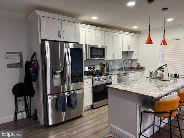 kitchen with backsplash, a kitchen island, a kitchen bar, appliances with stainless steel finishes, and wood finished floors