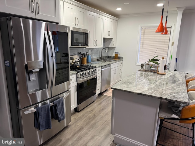 kitchen with ornamental molding, a kitchen breakfast bar, stainless steel appliances, and a sink