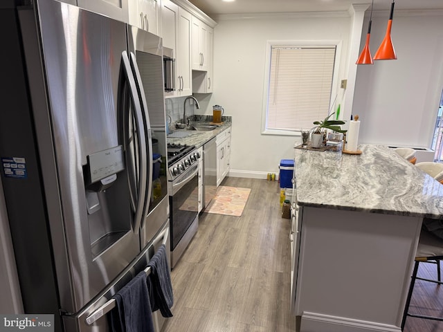 kitchen featuring crown molding, a breakfast bar, wood finished floors, stainless steel appliances, and a sink