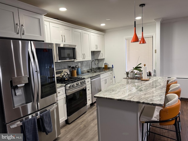 kitchen featuring a kitchen bar, a sink, a center island, appliances with stainless steel finishes, and decorative backsplash