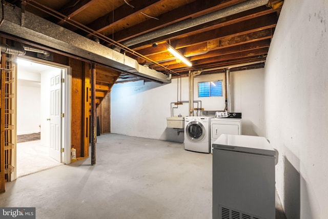 unfinished below grade area with a sink, fridge, and washing machine and clothes dryer