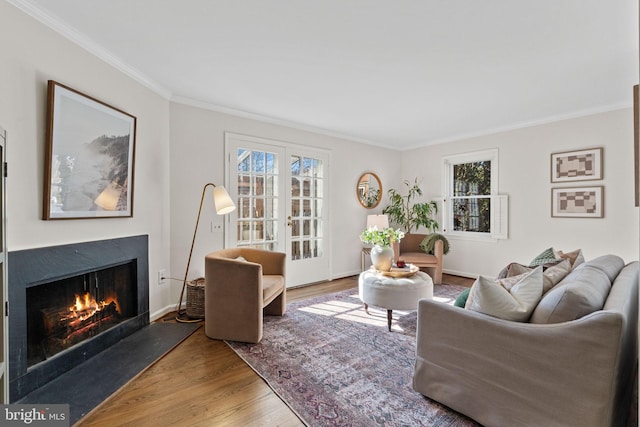 living room with crown molding, plenty of natural light, wood finished floors, and a warm lit fireplace