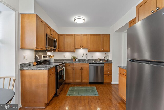 kitchen featuring a sink, brown cabinets, dark wood-type flooring, and appliances with stainless steel finishes