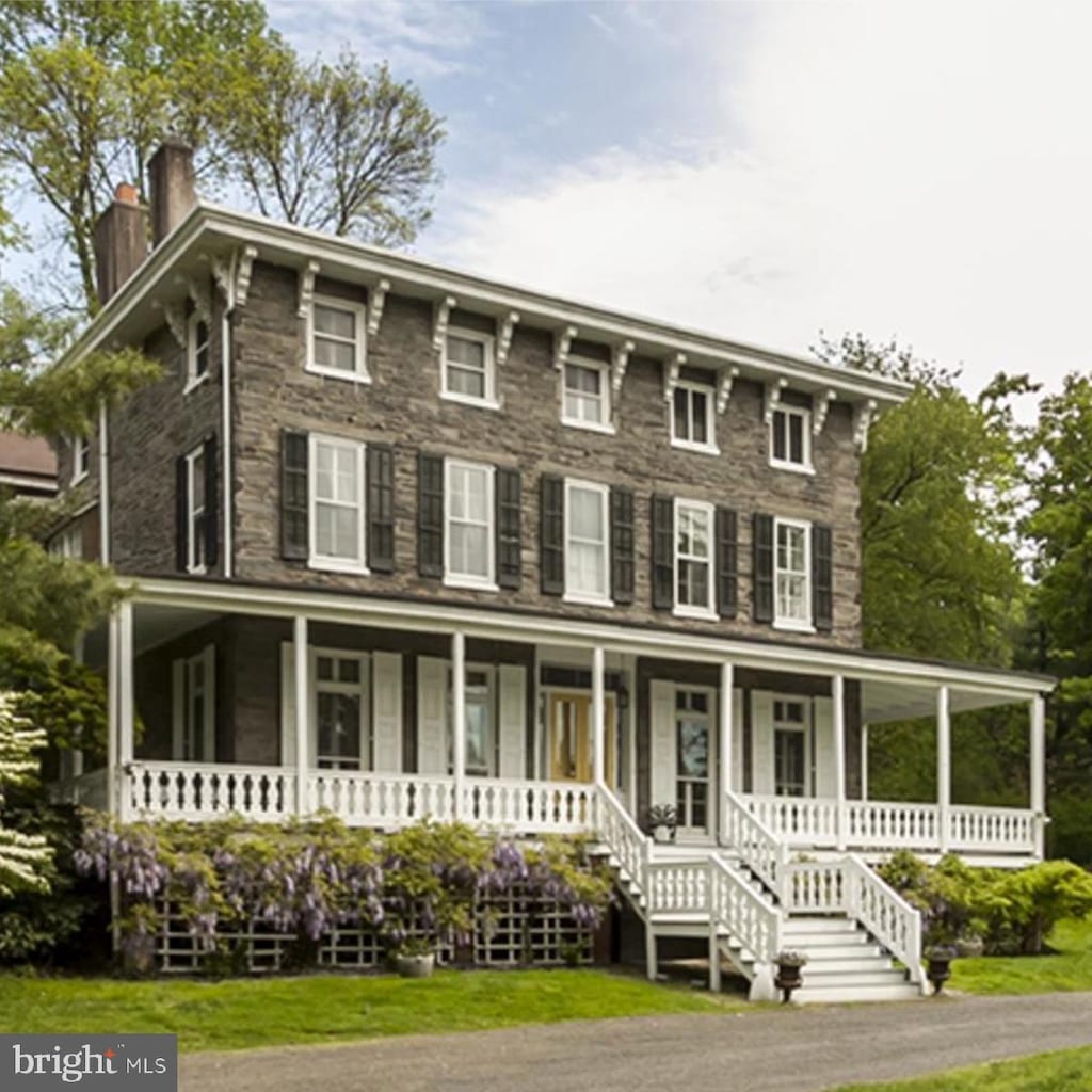 view of front of house featuring covered porch, a chimney, and a front yard