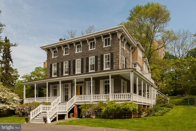 italianate-style house with a chimney, covered porch, and a front yard