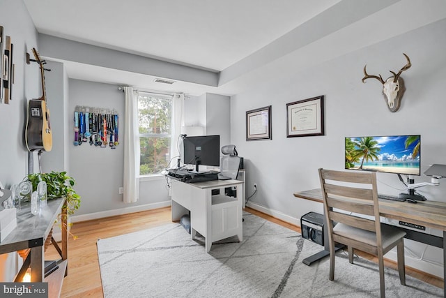 office area with light wood-type flooring, baseboards, and visible vents