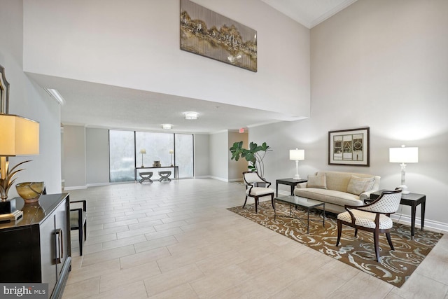 living area with floor to ceiling windows, a high ceiling, and baseboards