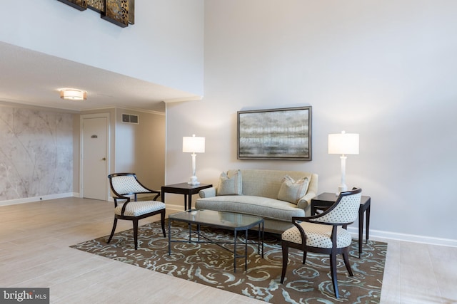 living area featuring wood finished floors, a high ceiling, baseboards, and visible vents