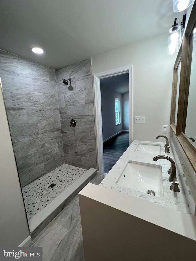 full bath with double vanity, a tile shower, and a sink