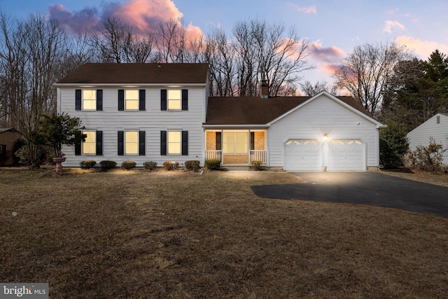 view of front of house featuring a front yard, an attached garage, driveway, and a chimney