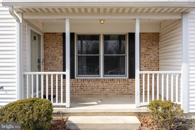 property entrance with a porch and brick siding