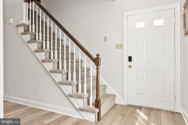 entryway with stairway, baseboards, and wood finished floors