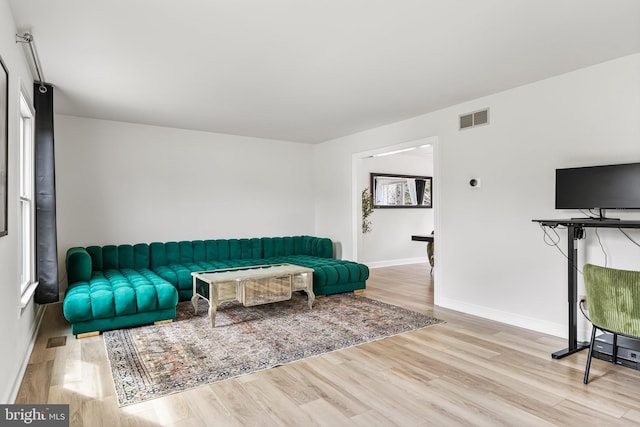 living room featuring visible vents, baseboards, and wood finished floors