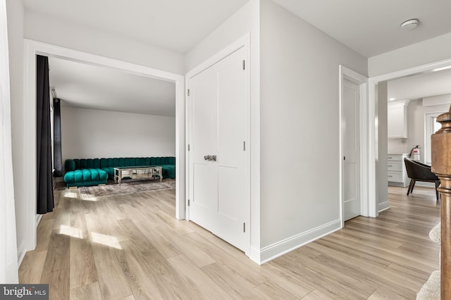 corridor featuring light wood-style floors and baseboards