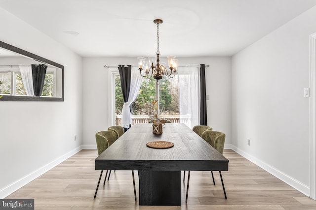 dining area with baseboards, a chandelier, and light wood finished floors