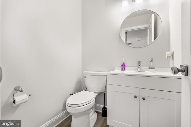 bathroom featuring toilet, vanity, baseboards, and wood finished floors