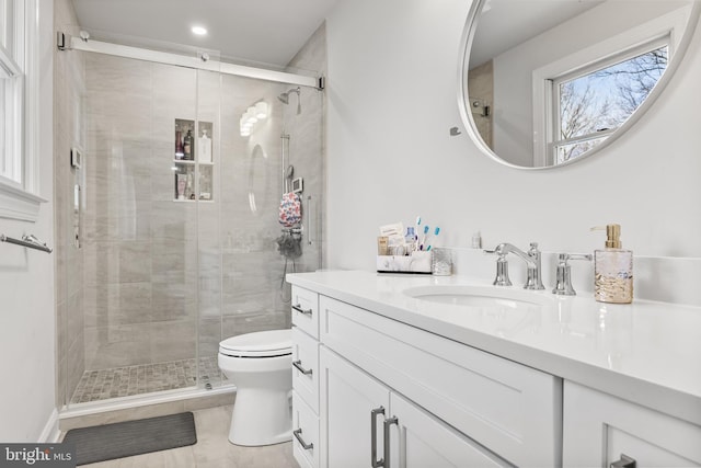 bathroom featuring a stall shower, toilet, and vanity