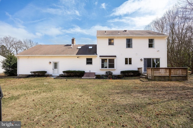 back of property with a wooden deck, a chimney, a yard, and a shingled roof