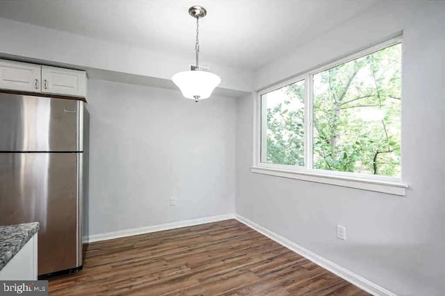 unfurnished dining area with baseboards and dark wood-style flooring