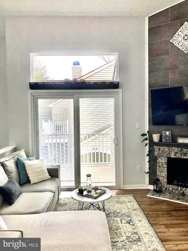 living room featuring a fireplace, wood finished floors, baseboards, and a textured ceiling