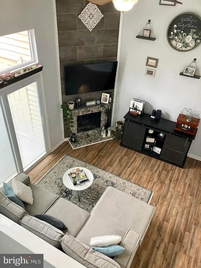 living room featuring a tile fireplace, baseboards, and wood finished floors