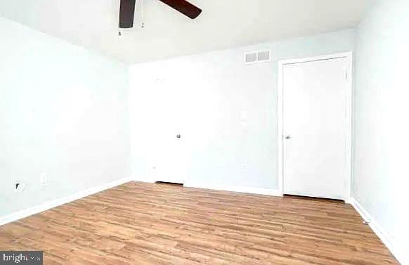 spare room with visible vents, baseboards, wood finished floors, and a ceiling fan