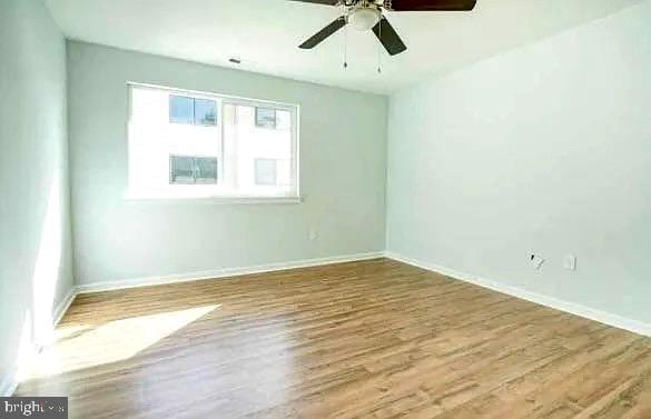 spare room featuring wood finished floors, baseboards, and ceiling fan