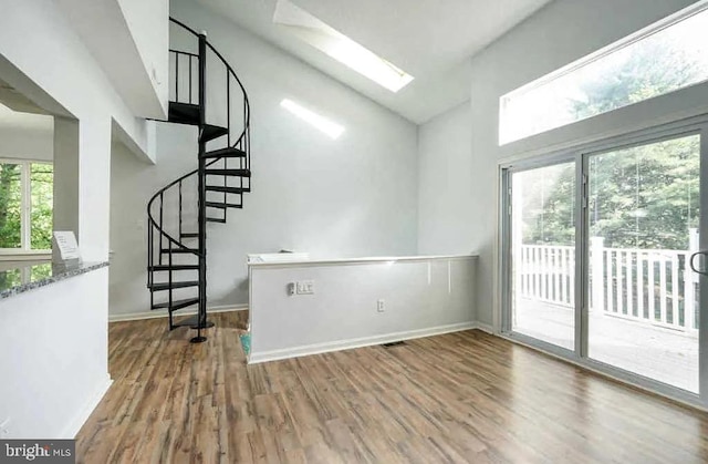 interior space with a skylight, baseboards, wood finished floors, and stairs