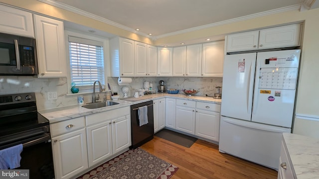 kitchen featuring black appliances, ornamental molding, a sink, wood finished floors, and white cabinetry