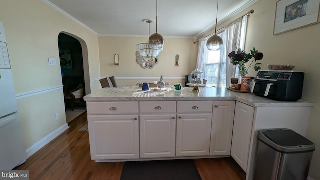 kitchen featuring light countertops, ornamental molding, arched walkways, dark wood-style floors, and white cabinetry