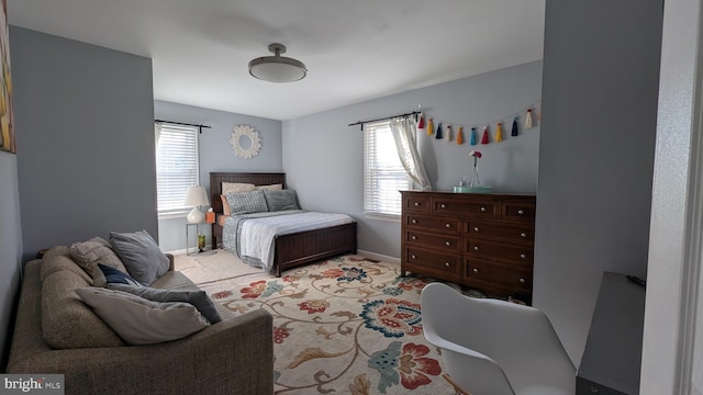 bedroom with baseboards, multiple windows, and light carpet