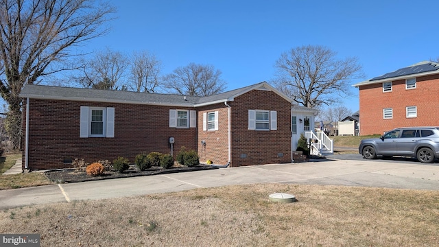 view of front of house featuring a front lawn, concrete driveway, brick siding, and crawl space