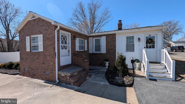 view of front of property featuring crawl space, fence, brick siding, and a chimney