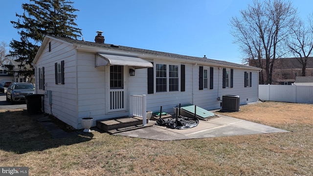 back of house featuring a yard, central air condition unit, a chimney, and fence