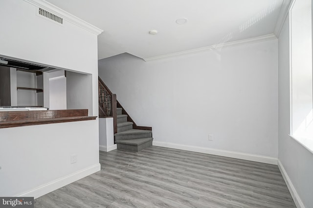 unfurnished room with visible vents, crown molding, baseboards, stairway, and wood finished floors