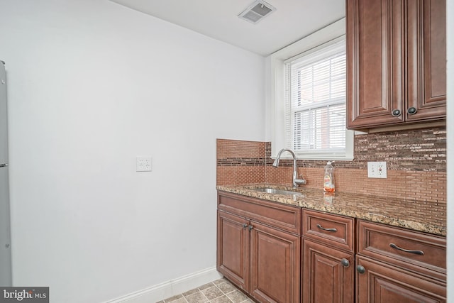 kitchen featuring a sink, visible vents, light stone countertops, and decorative backsplash