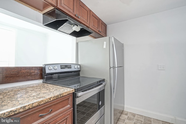 kitchen with stainless steel electric range, baseboards, freestanding refrigerator, and brown cabinets