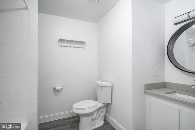 bathroom featuring baseboards, toilet, wood finished floors, and vanity