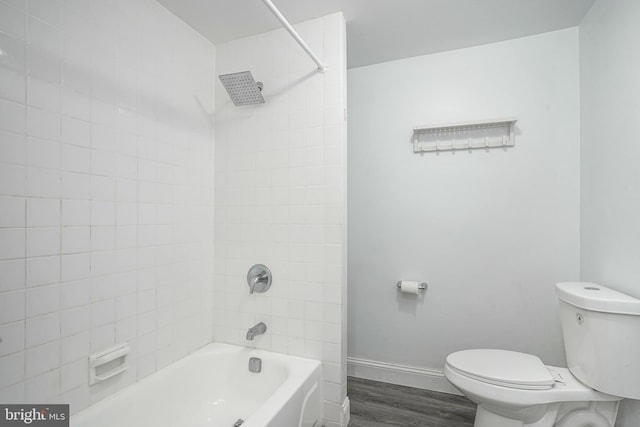 full bath with toilet, wood finished floors, baseboards, and shower / washtub combination