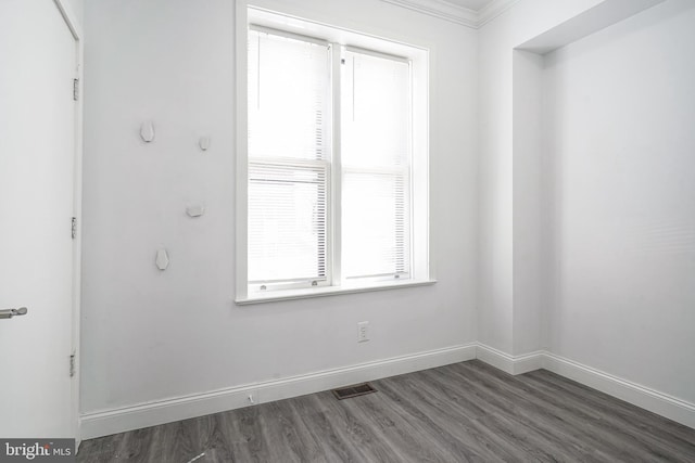 empty room featuring visible vents, wood finished floors, and baseboards