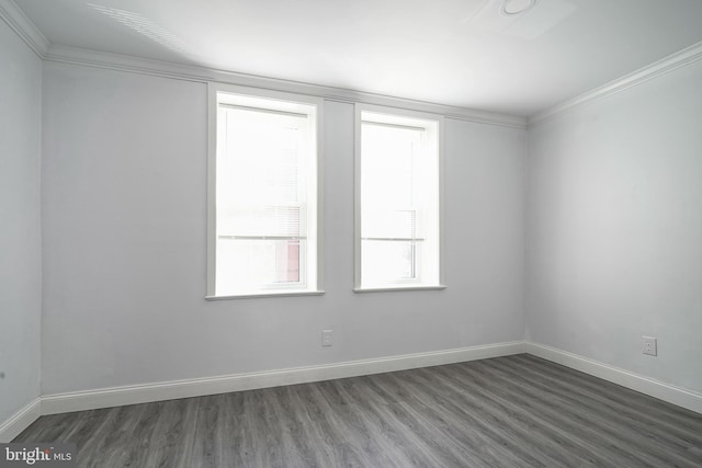 empty room featuring wood finished floors, baseboards, and ornamental molding