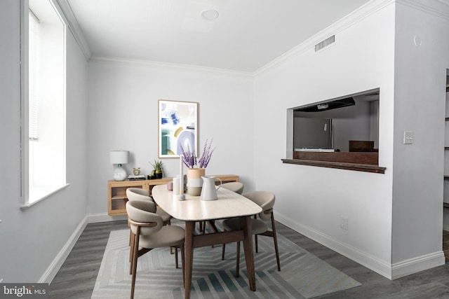 dining space with visible vents, baseboards, wood finished floors, and crown molding