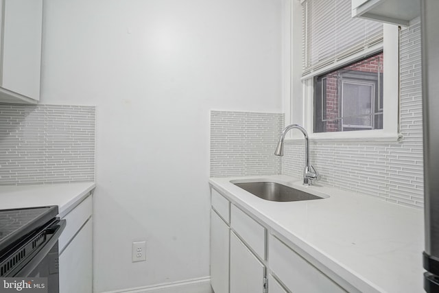 kitchen with a sink, backsplash, and white cabinetry