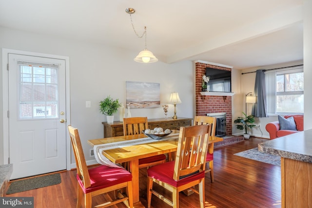 dining area featuring a brick fireplace, wood finished floors, and baseboards