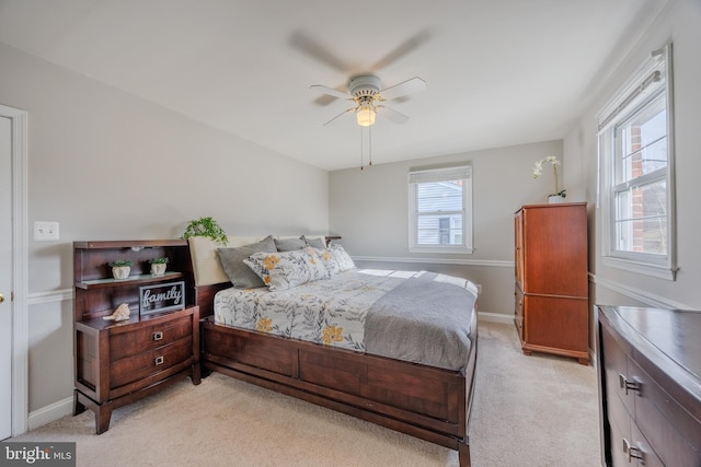 bedroom featuring baseboards, light colored carpet, and a ceiling fan