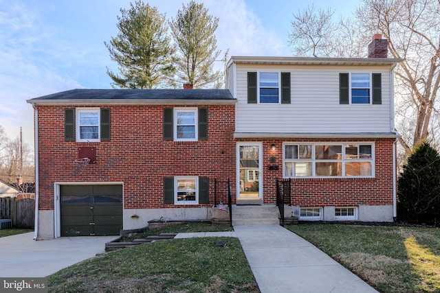 tri-level home with a front lawn, brick siding, driveway, and a chimney