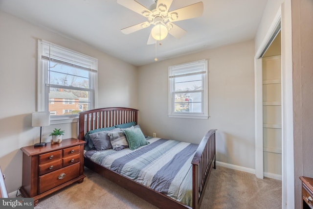 bedroom featuring baseboards, light colored carpet, and a ceiling fan